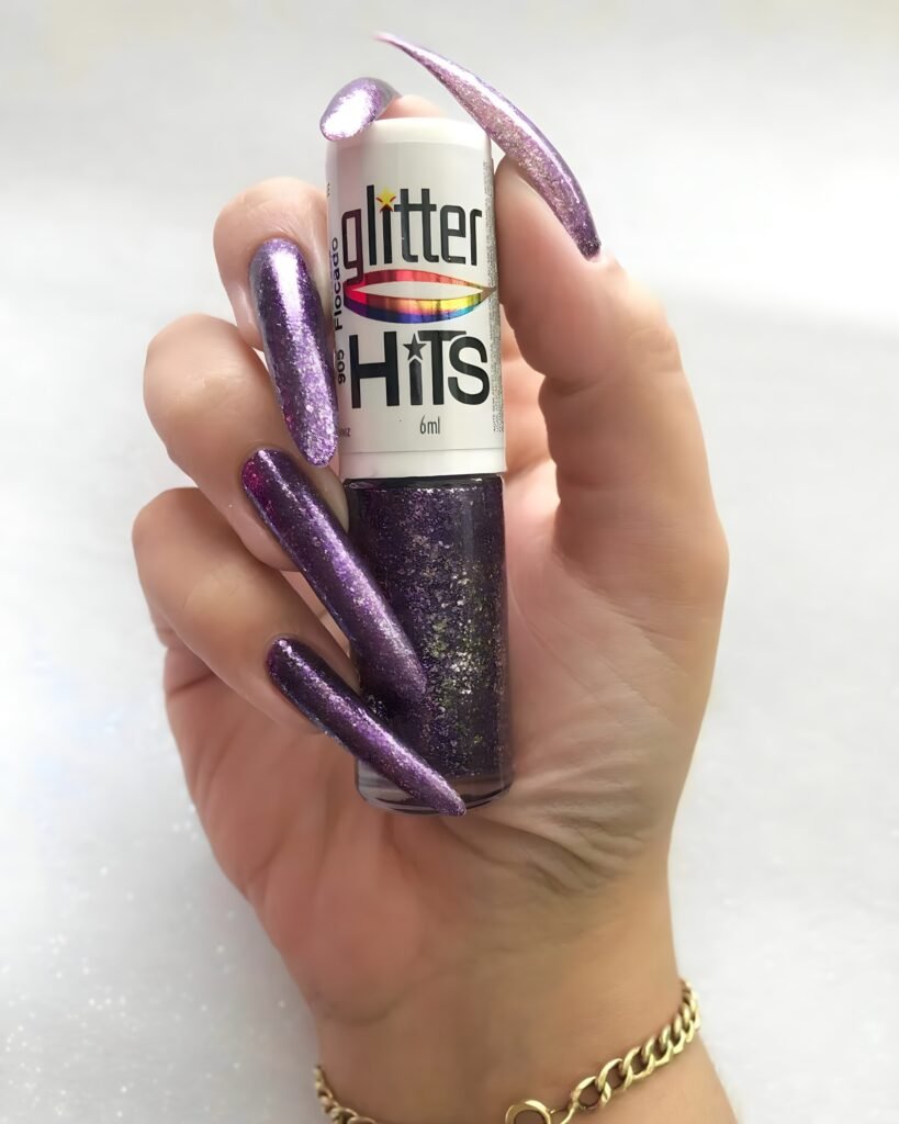 Guwahati BDSM Mistress Anu displaying long glitter nails holding nail polish highlighting shiny nail art and stylish hand presentation