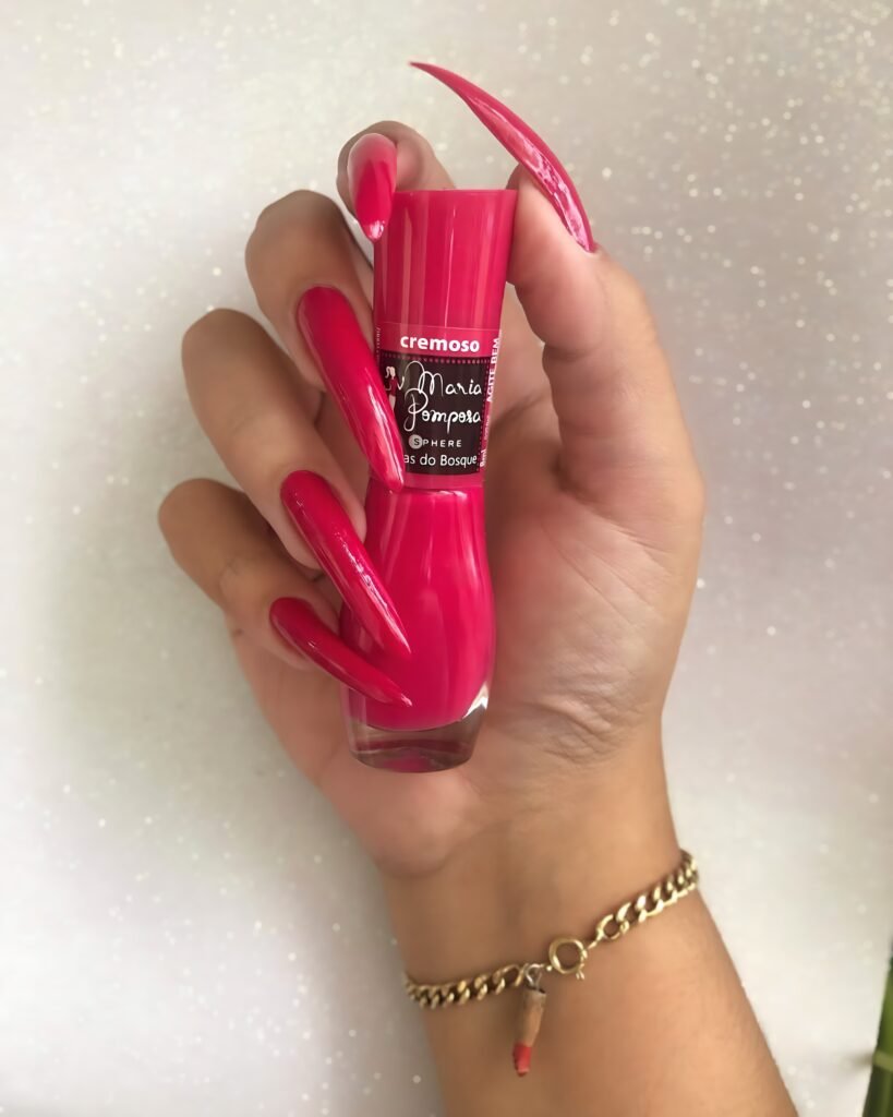 Raipur BDSM Mistress Anu showcasing long red nails holding nail polish highlighting bold nail art and elegant hand styling