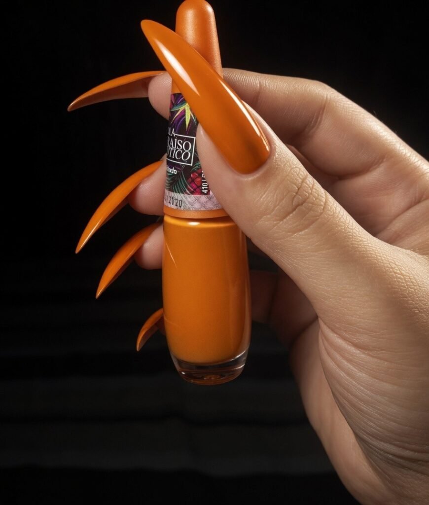 Surat BDSM Mistress Anu showcasing long sharp nails holding orange nail polish highlighting bold nail fashion style