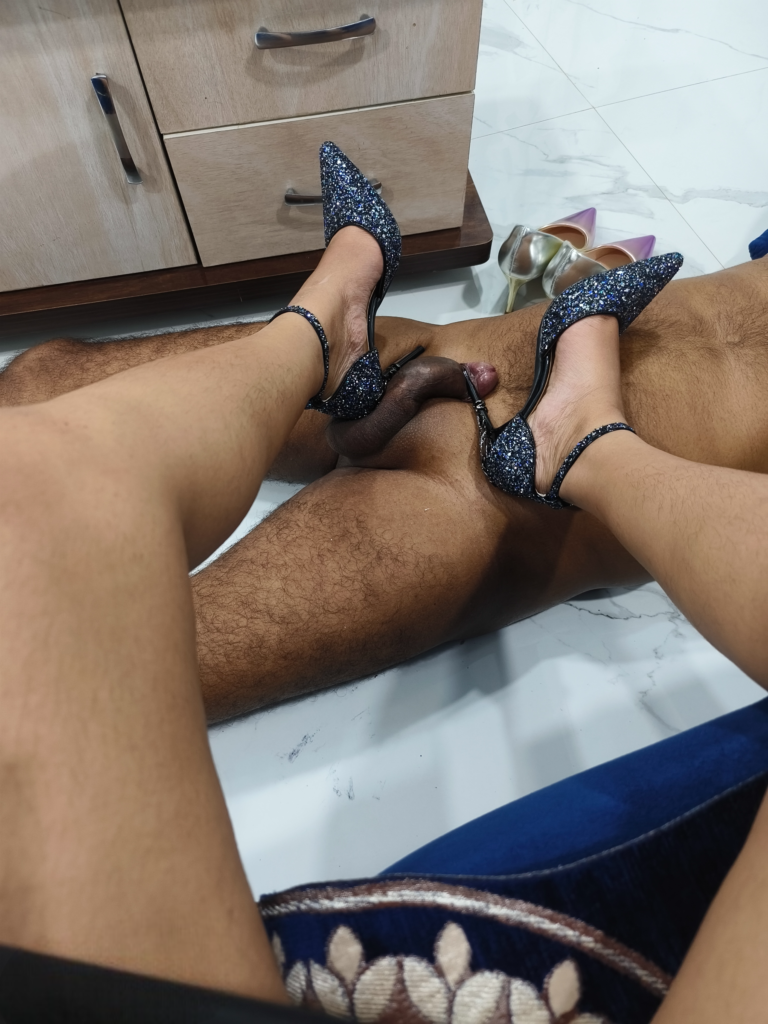 George Town BDSM Mistress Anu wearing blue glitter stiletto heels while standing on a submissive male partner during a dominant session.